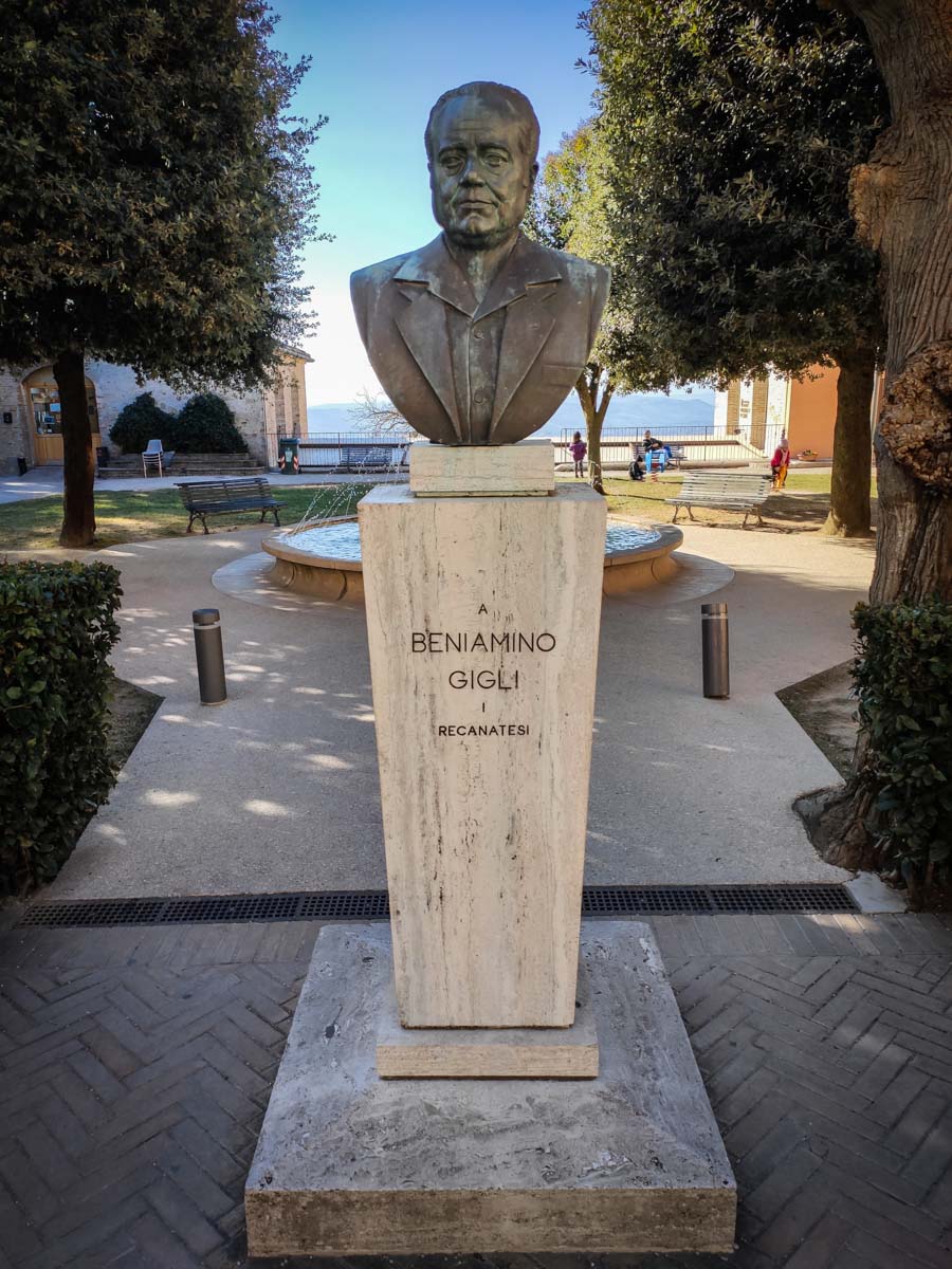 busto bronzeo di Beniamino Gigli su basamento in travertino nei giardini pubblici di Recanati, con le colline sullo sfondo