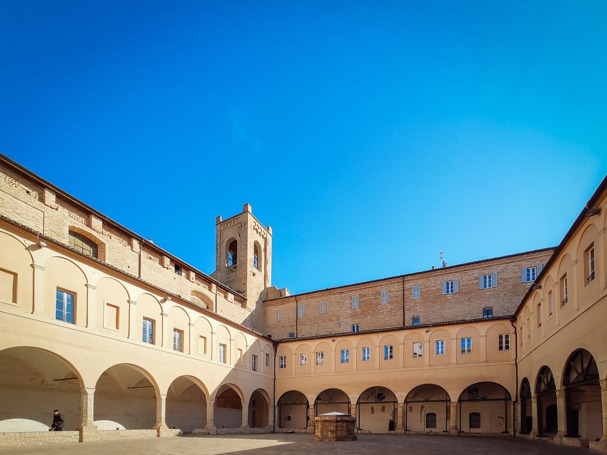 chiostro del complesso di Sant'Agostino a Recanati con il portico e la Torre del Passero Solitario sullo sfondo