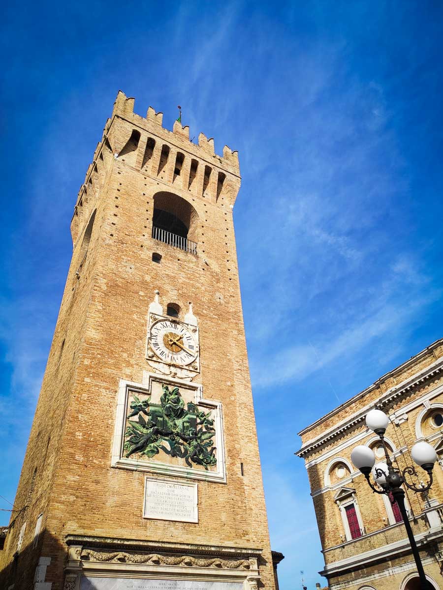 la Torre del Borgo di Recanati in laterizio con merlature e grande orologio, in Piazza Giacomo Leopardi