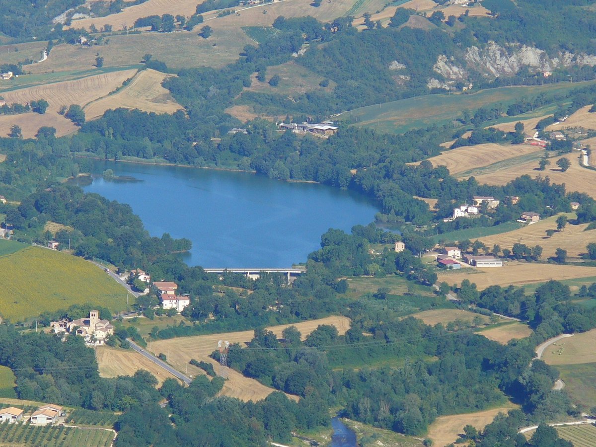 il Lago di San Ruffino visto dall'alto da Smerillo, specchio d'acqua blu tra campi coltivati, boschi e casolari